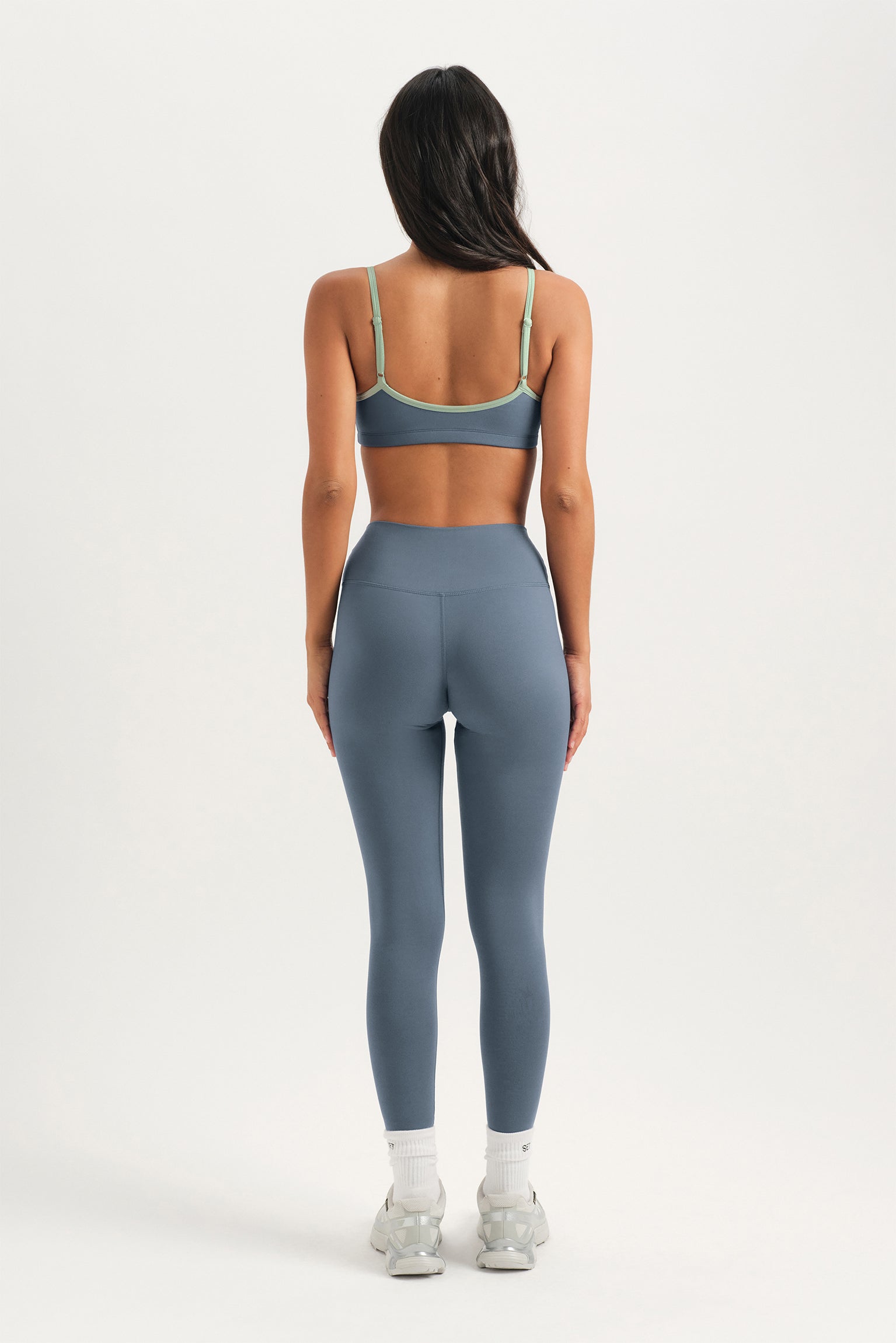 Person wearing a gray sports bra and leggings set on a white background