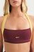 Woman wearing a maroon sports bra with yellow straps and 'SET' branding.