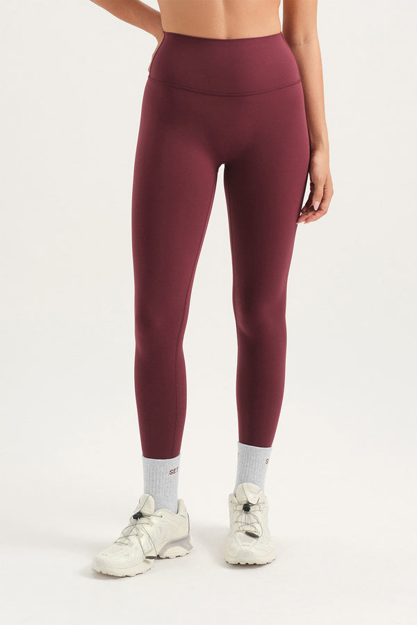 Maroon leggings worn by a person on a white background 