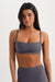 Woman wearing a gray sports bra and leggings on a white background <model-info>Sydnee wears a size XS and is 5'8", 22” waist, 32BB bust.</model-info>
