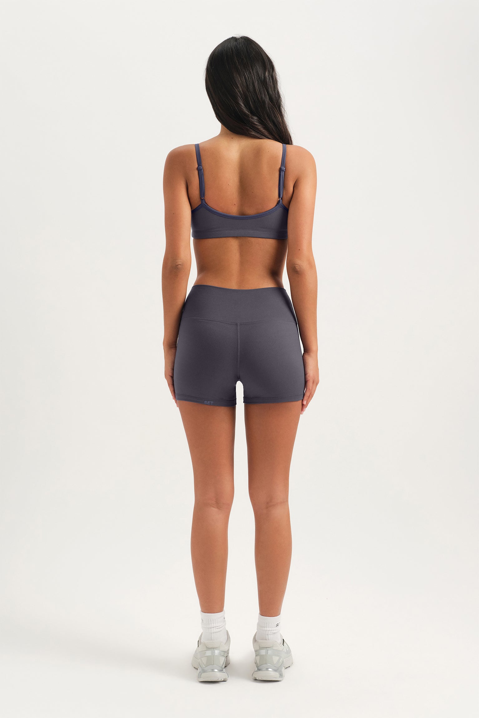 Person wearing a gray sports bra and shorts set on a white background