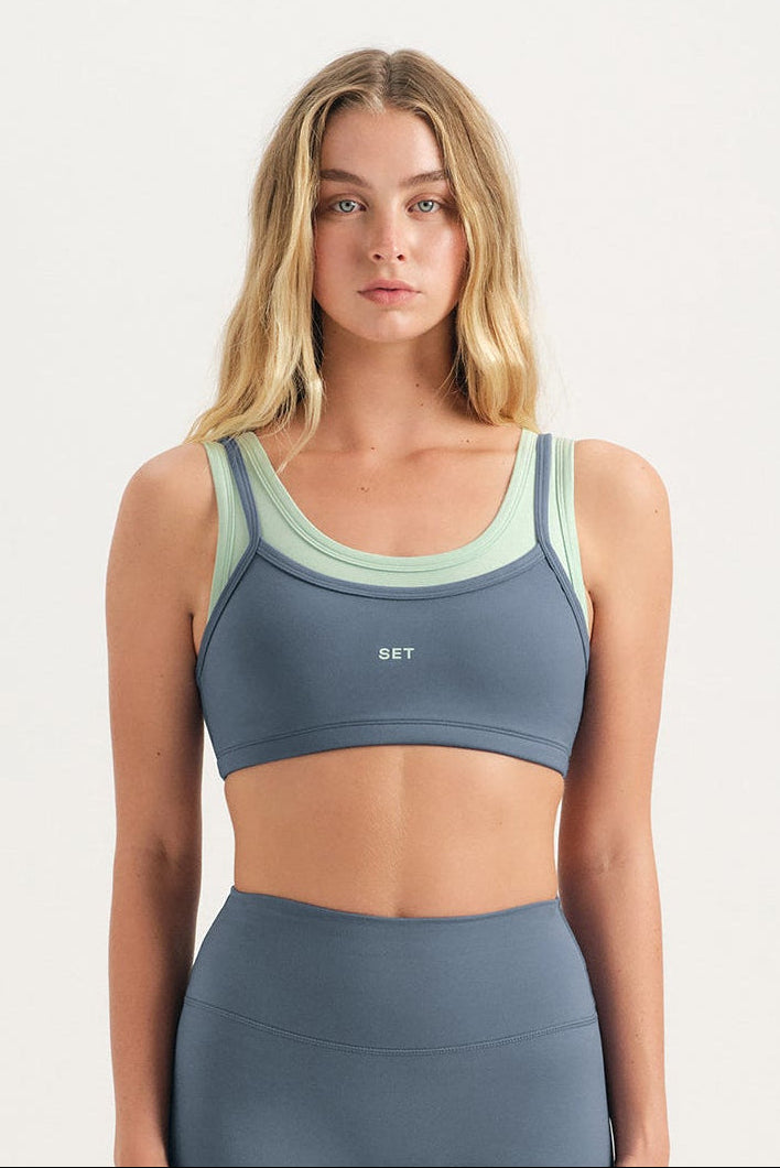 Woman wearing a gray sports bra and shorts set on a white background