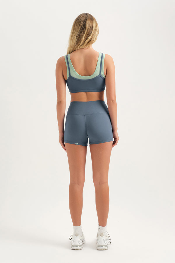 Person wearing a sports bra and shorts set on a white background