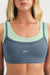 Blue sports bra with green straps worn by a person on a white background