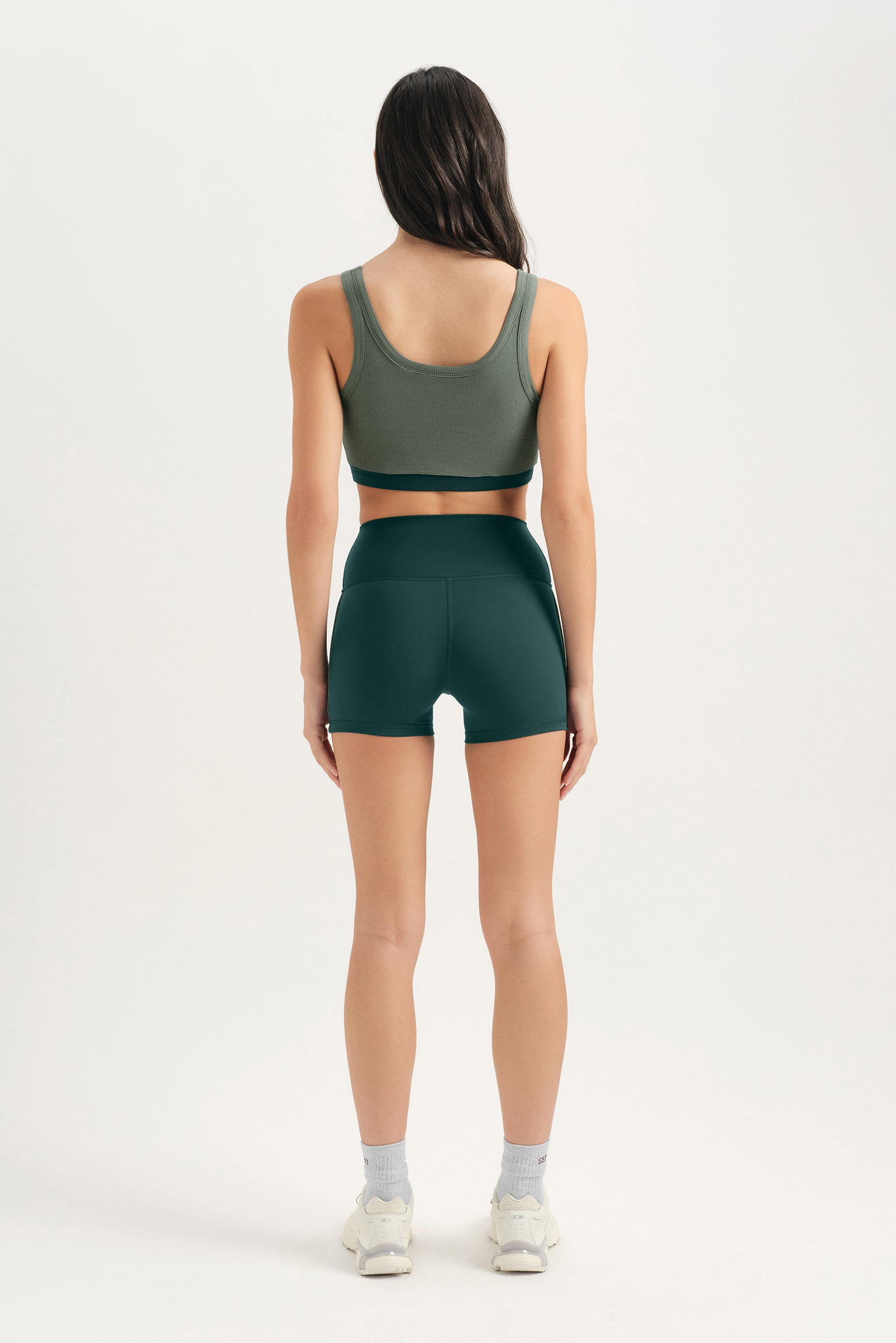Person wearing a green sports bra and shorts set on a white background