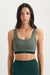 Woman wearing a green sports bra and leggings on a white background <model-info>Casey wears a size S and is 5’9”, 24” waist, 32B bust.</model-info>