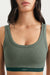 Green sports bra worn by a person on a plain background