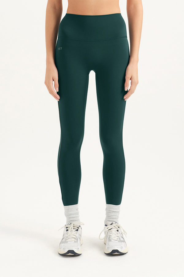Person wearing dark green leggings on a white background 