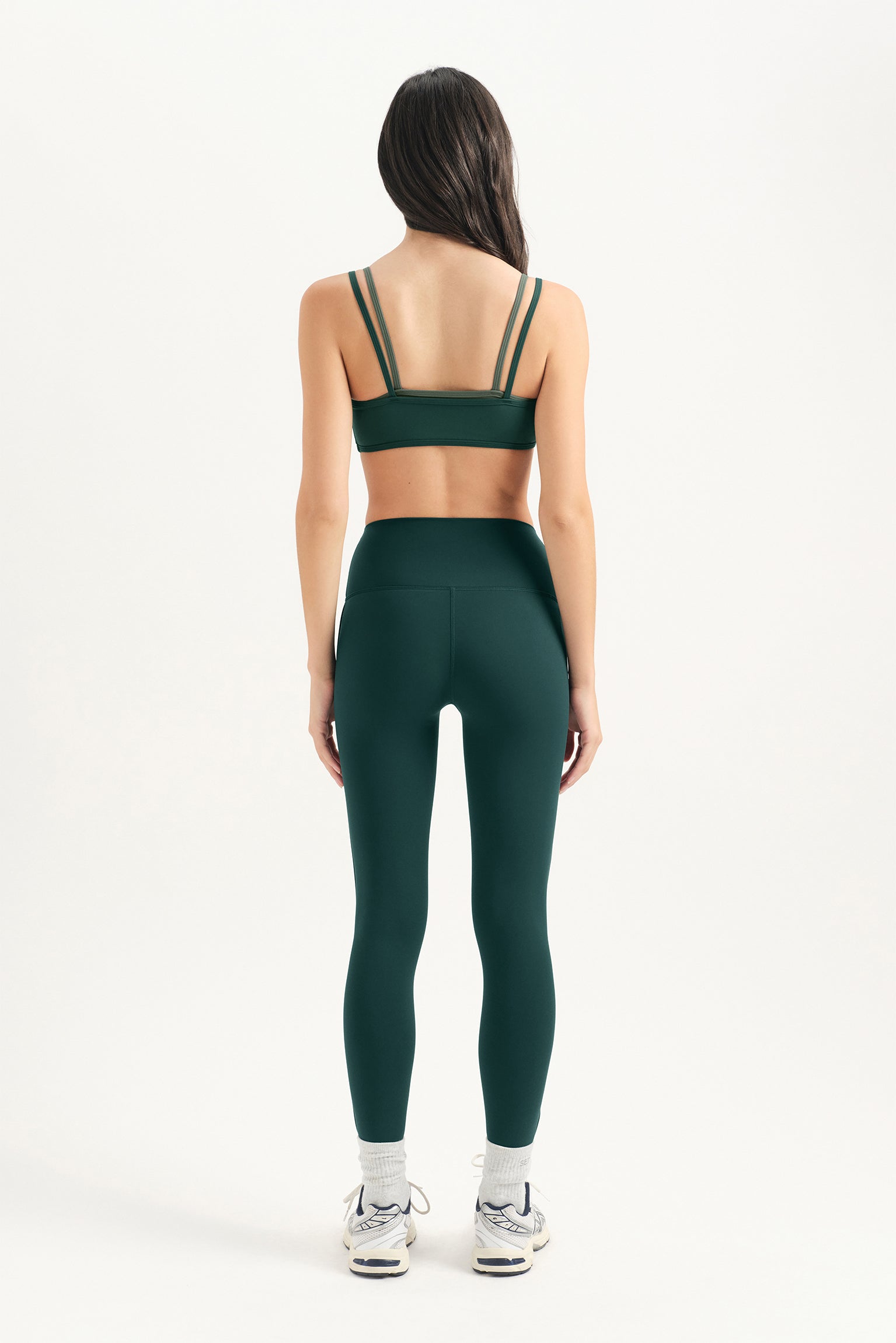 Person wearing a green sports bra and leggings set on a white background