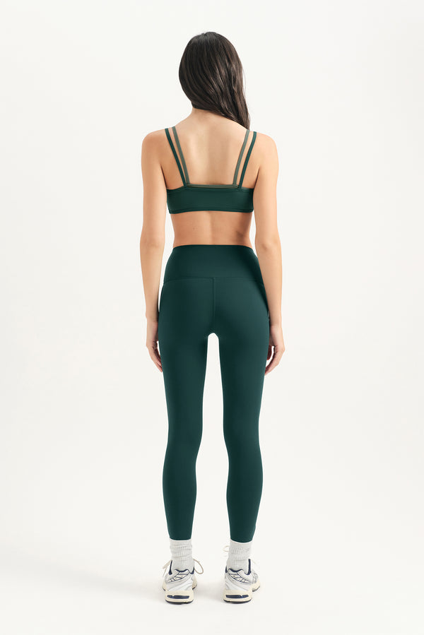 Person wearing a green sports bra and leggings set on a white background