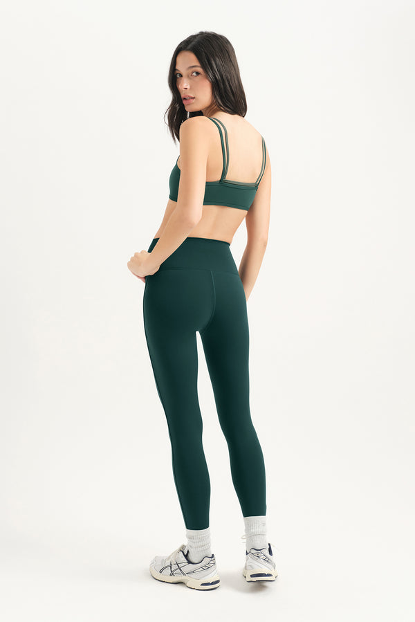 Woman wearing a green sports bra and leggings set on a white background