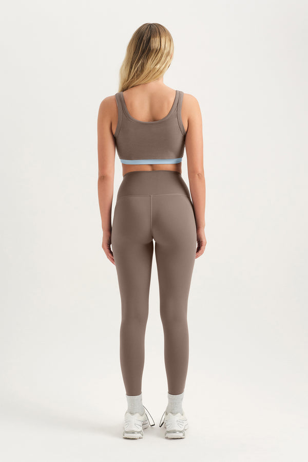 Person wearing a brown sports bra and leggings set on a white background