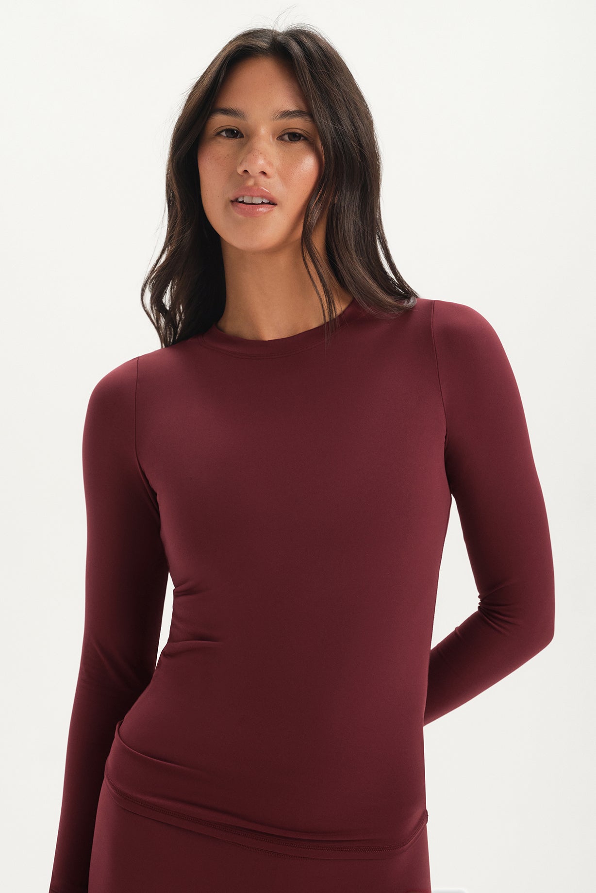 Woman wearing a burgundy long-sleeve top on a white background <model-info>Jelene wears a size XS and is 5’7”, 23” waist, 32AB bust.</model-info>