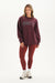 Woman wearing a maroon 'SET' sweatshirt and leggings on a white background