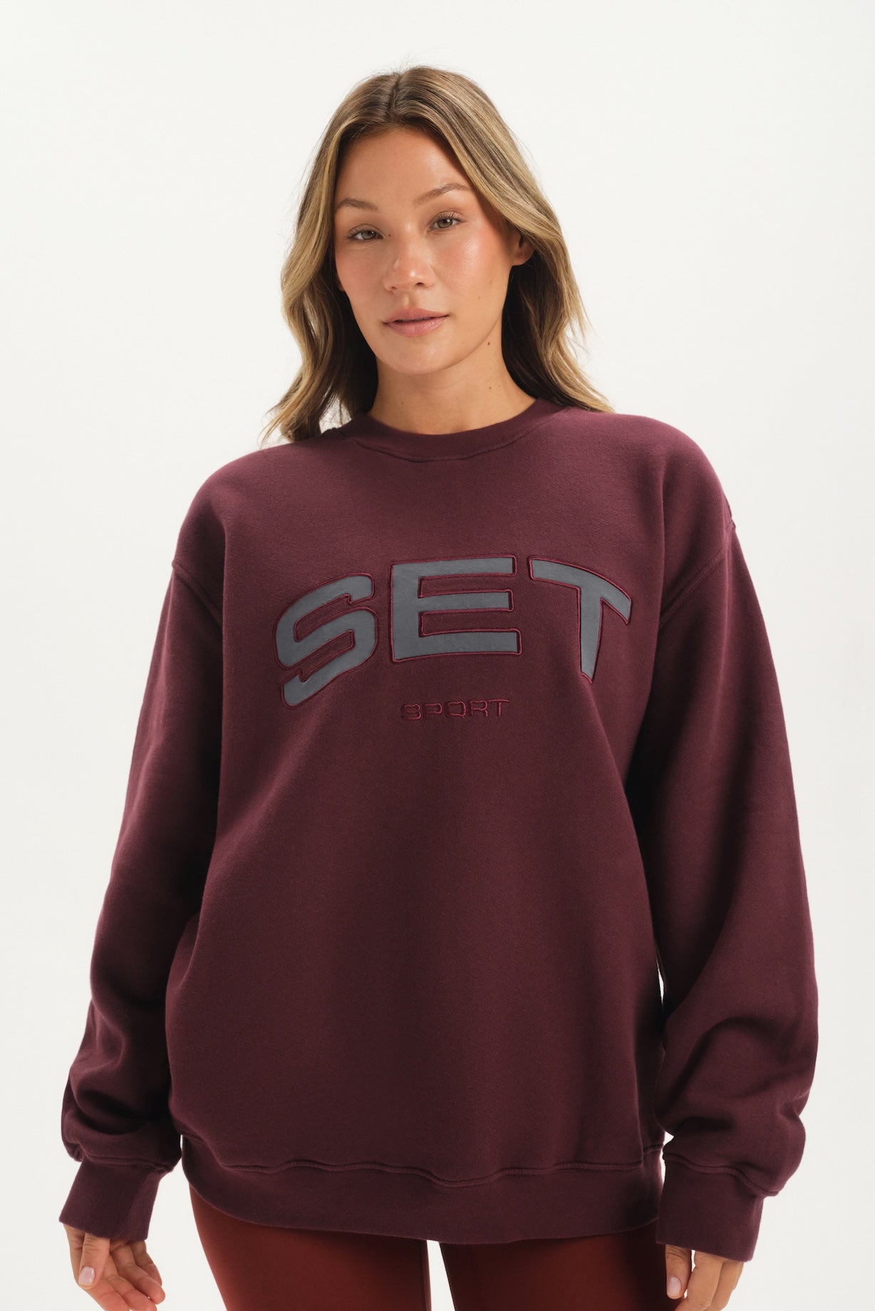 Woman wearing a maroon sweatshirt with 'SET' printed on it against a white background <model-info>Bre wears a size M and is 5’7”, 25½" waist, 33” bust.</model-info>