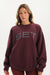 Woman wearing a maroon sweatshirt with 'SET' printed on it against a white background <model-info>Bre wears a size M and is 5’7”, 25½" waist, 33” bust.</model-info>