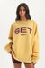 Woman wearing a yellow sweatshirt with 'SET Sport' text on a white background <model-info>Jelene wears a size L and is 5’7”, 23” waist, 32AB bust.</model-info>