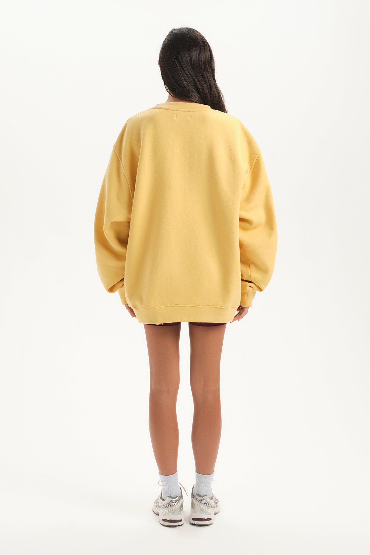 Person wearing a yellow oversized sweater on a white background