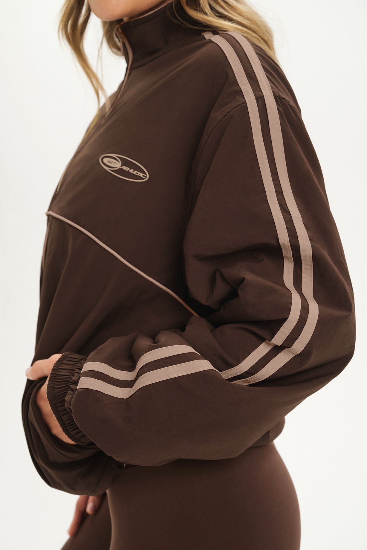 Brown tracksuit with white stripes on a plain background
