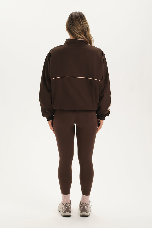 Person wearing a brown tracksuit on a white background