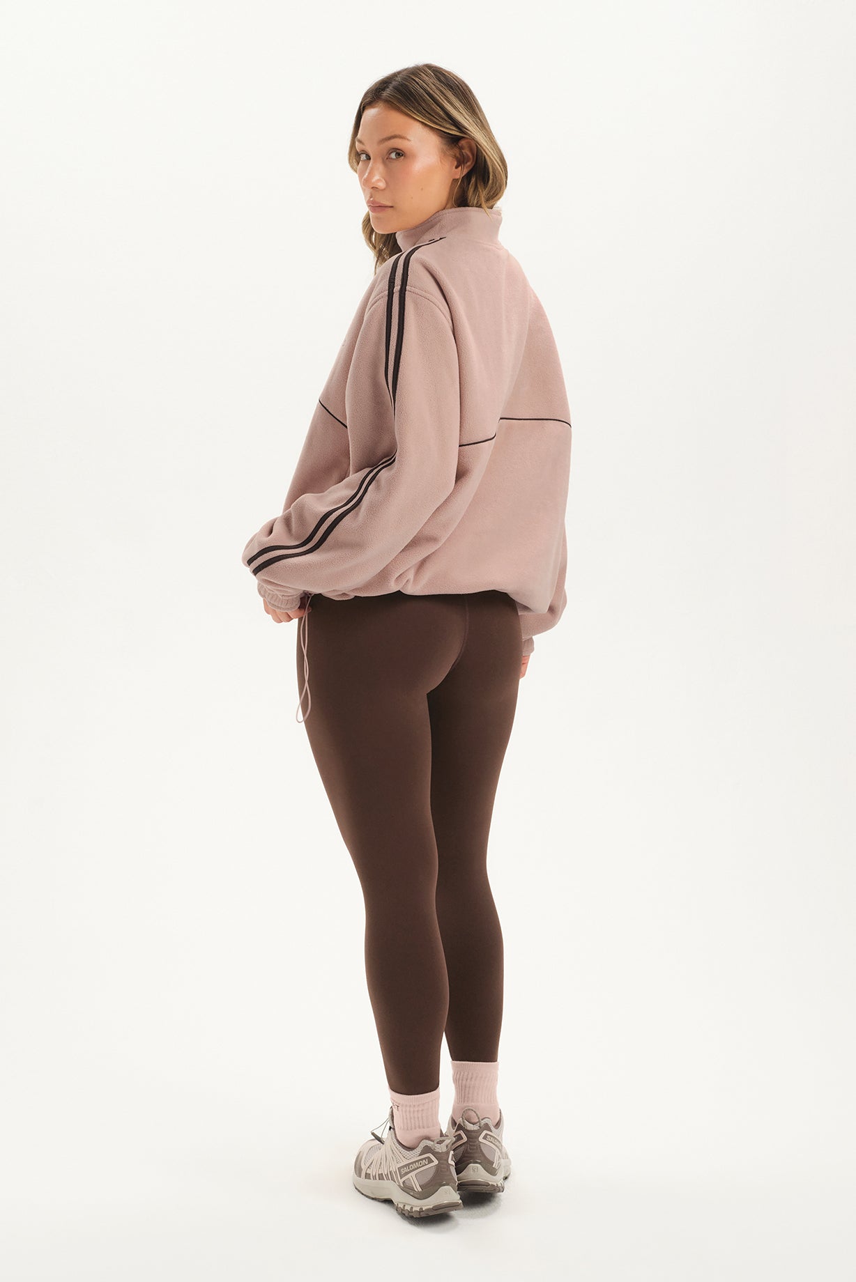 Woman wearing a pink tracksuit with a white background