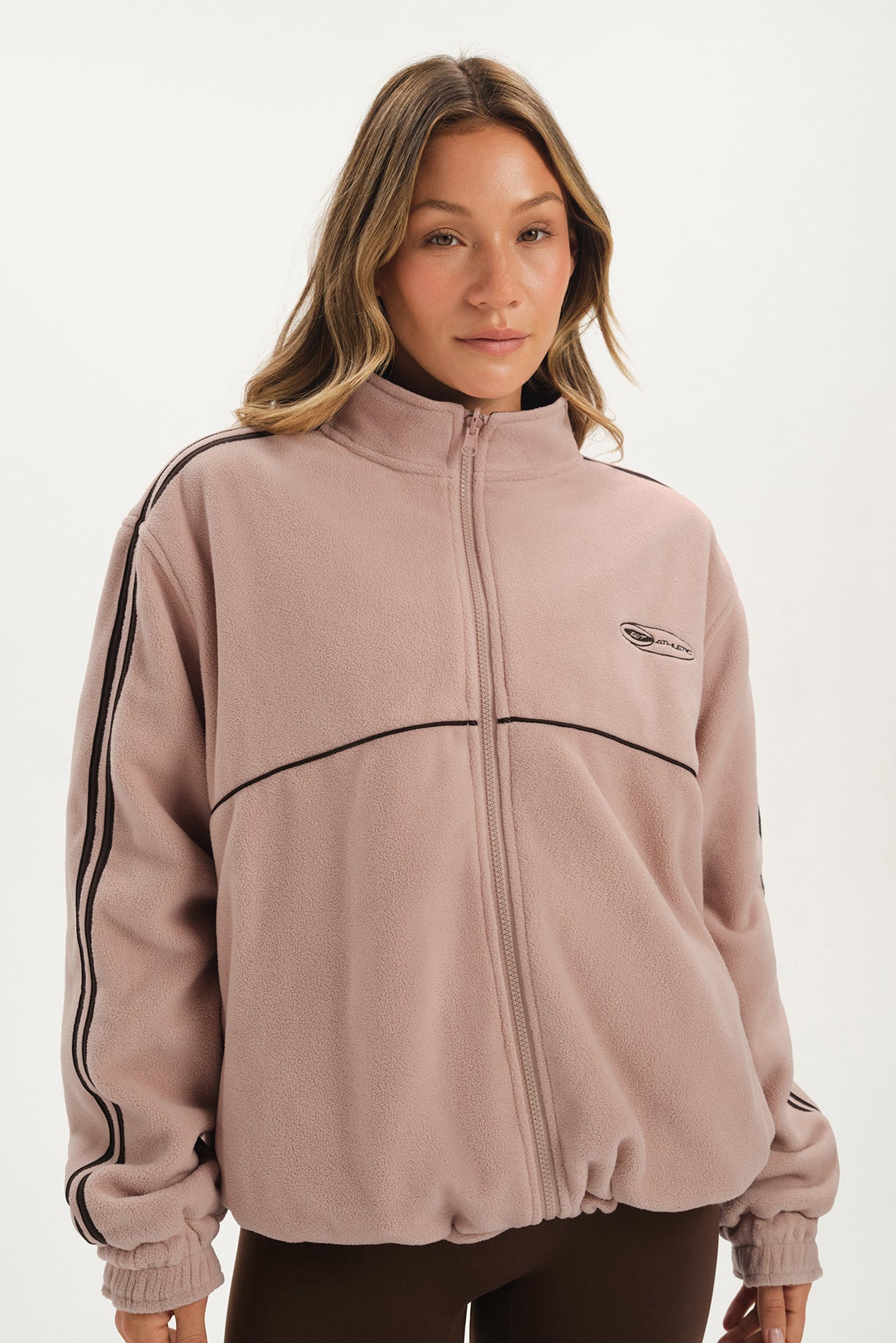 Woman wearing a mauve tracksuit with black stripes on a white background