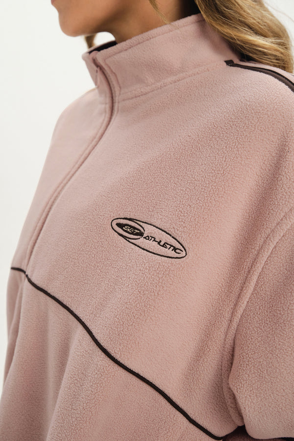 Close-up of a pink fleece pullover with a logo on a white background