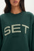 Green sweatshirt with 'SET' logo worn by a person