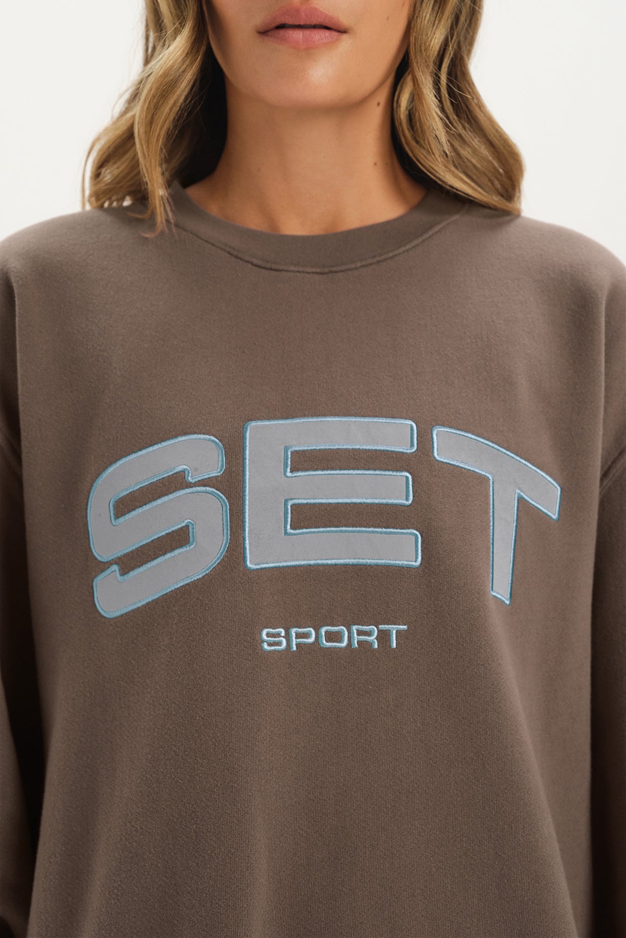 Brown sweatshirt with 'SET Sport' text on a plain background