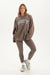 Woman wearing a brown 'SET' sweatshirt and leggings on a white background