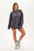 Woman wearing a gray oversized sweatshirt with 'SET' logo on a white background