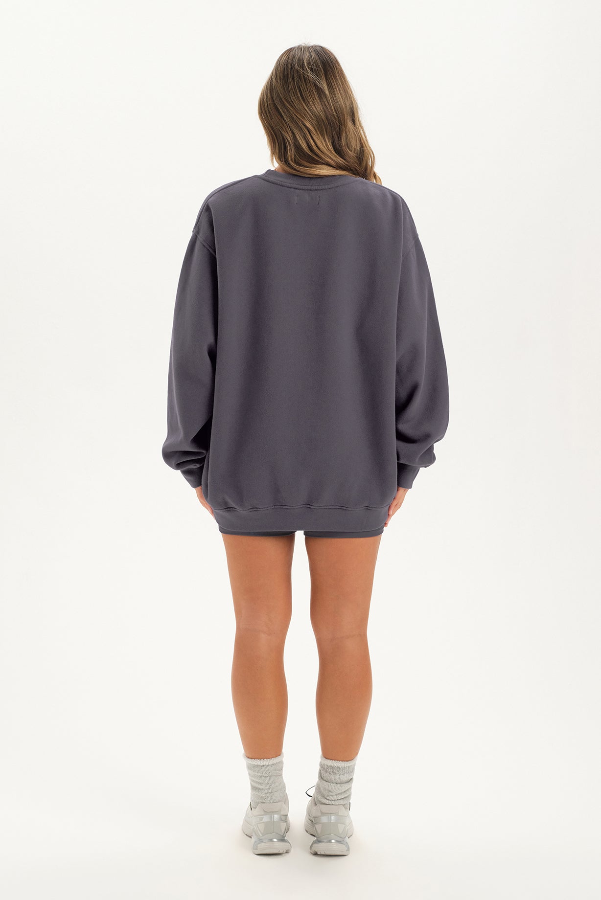 Person wearing a gray oversized sweatshirt on a white background