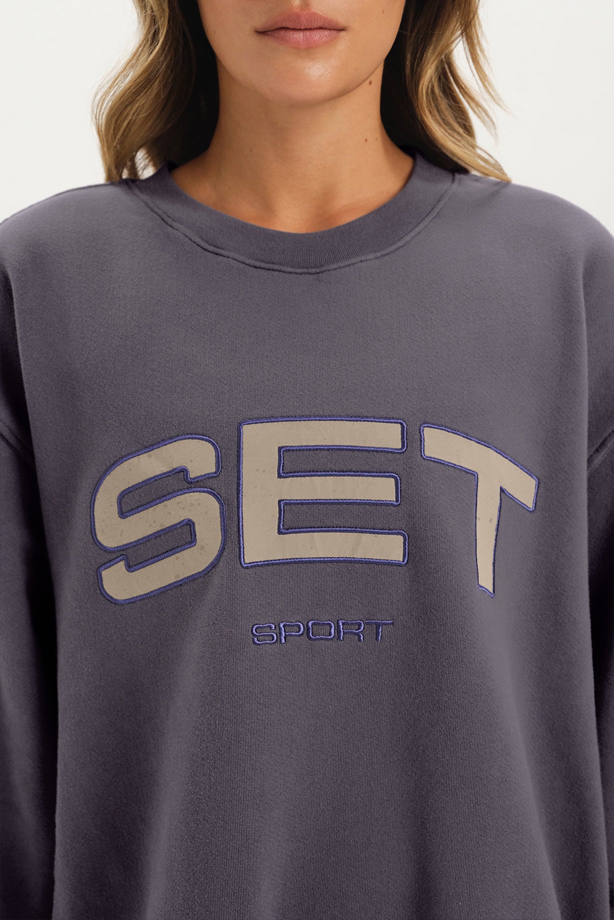Gray sweatshirt with 'SET Sport' text worn by a person