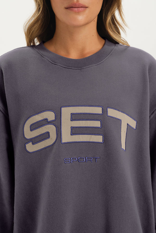 Gray sweatshirt with 'SET Sport' text worn by a person