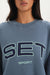 Gray sweatshirt with 'SET Sport' text worn by a person
