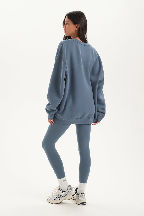 Person wearing a blue sweatshirt and leggings set on a white background