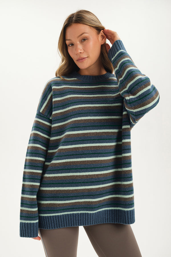 Woman wearing a blue and green striped sweater on a white background 