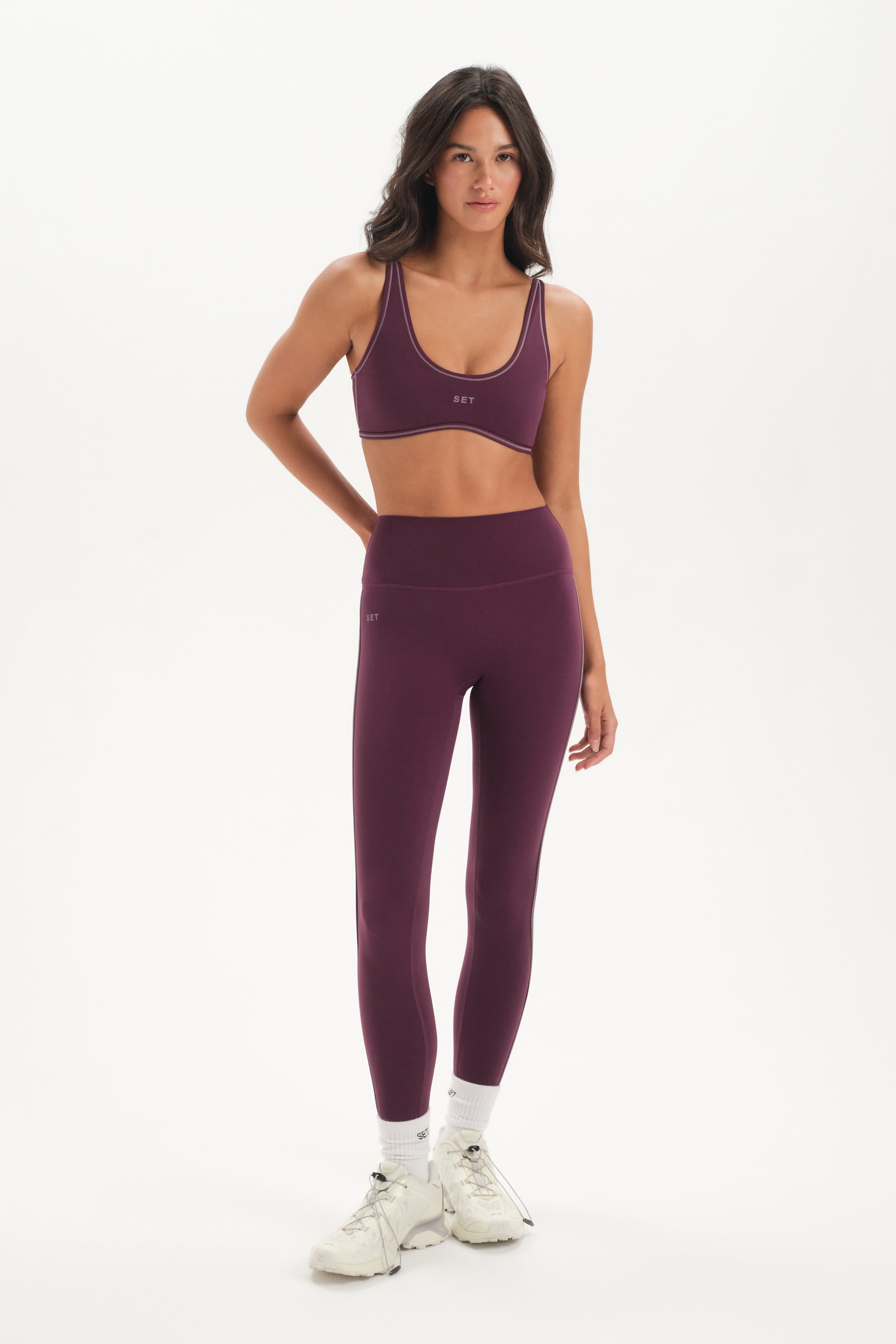 Woman wearing a purple sports bra and leggings set on a white background