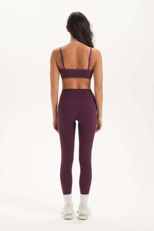 Person wearing a purple sports bra and leggings set on a white background