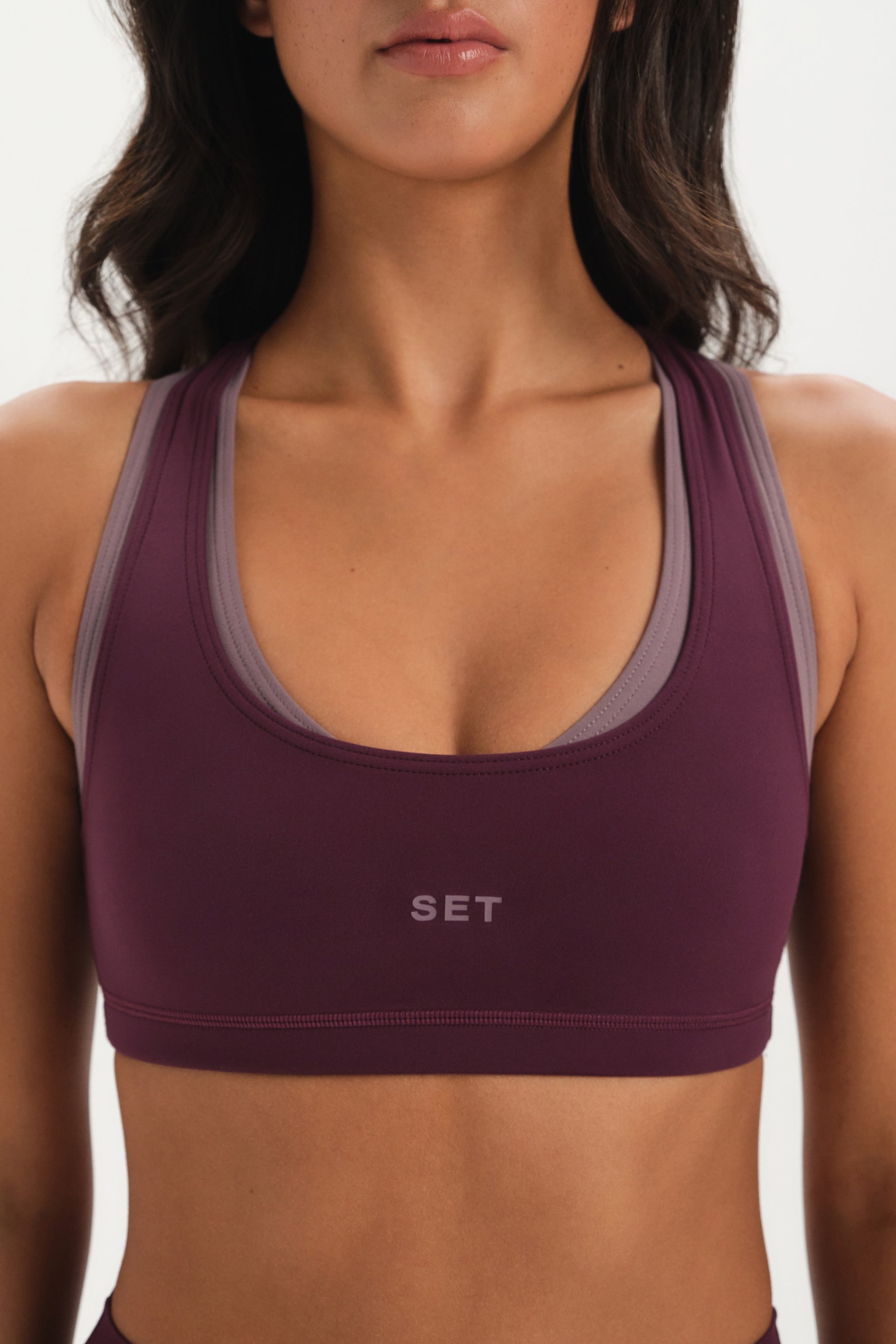 Purple sports bra with 'SET' logo worn by a person on a white background