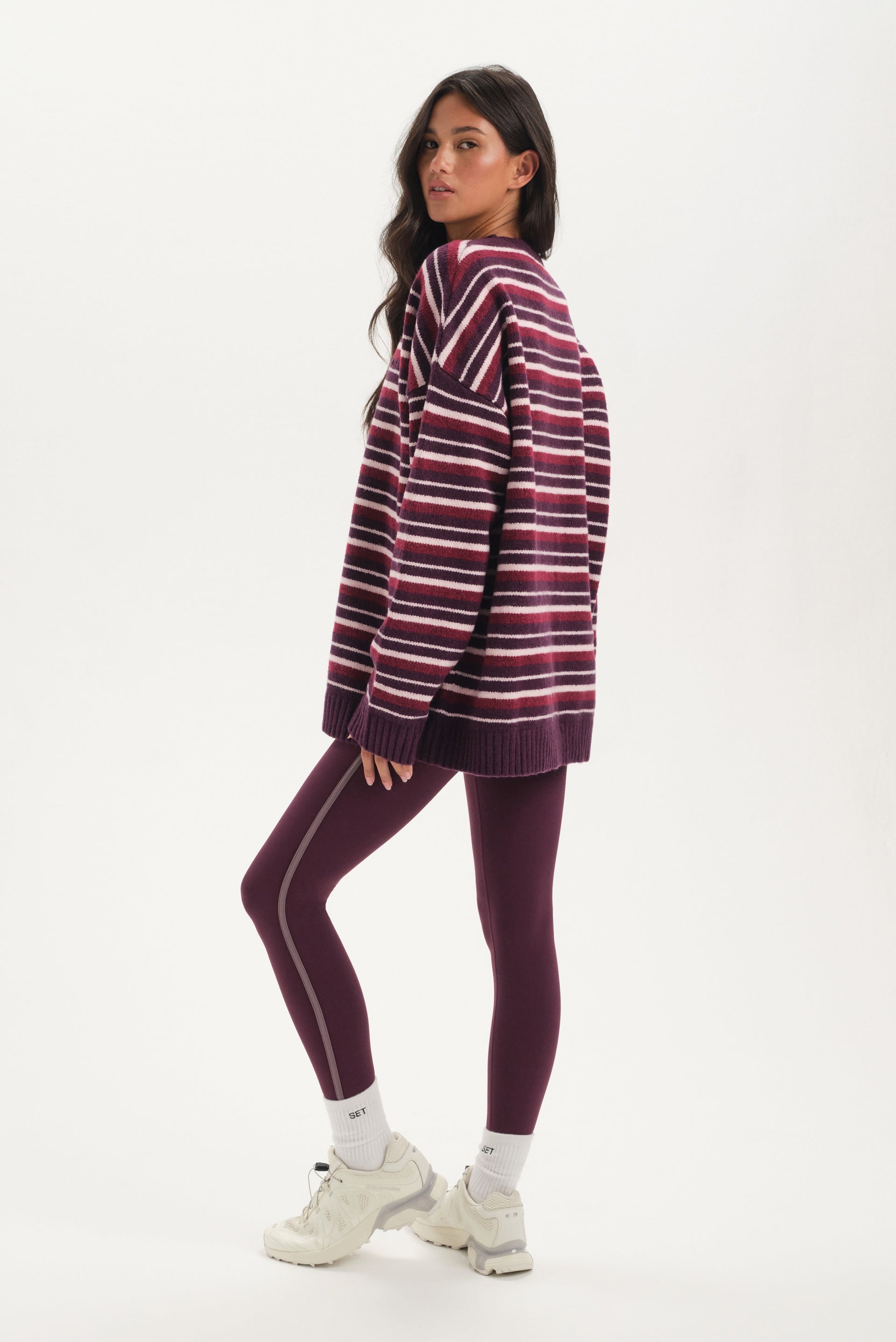 Woman wearing a striped hoodie and leggings on a white background