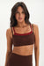 Woman wearing a brown sports bra and leggings on a white background <model-info>Jelene wears a size XS and is 5’7”, 23” waist, 32AB bust.</model-info>