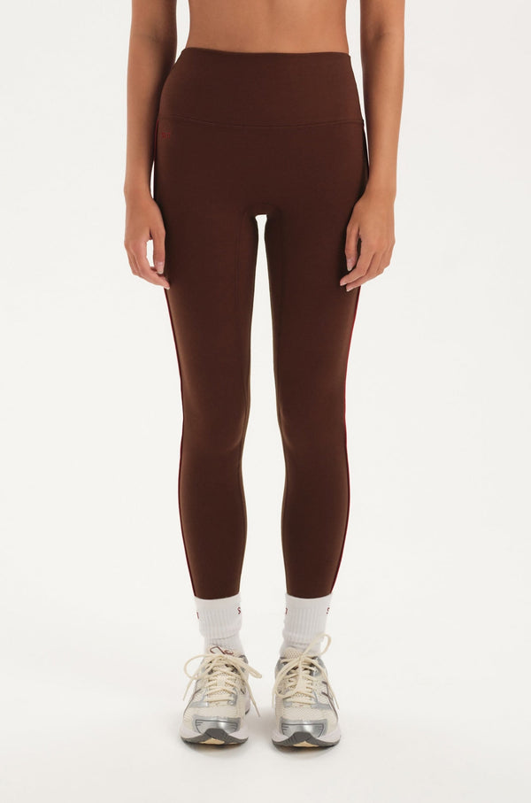 Woman wearing a brown sports bra and leggings set on a white background 