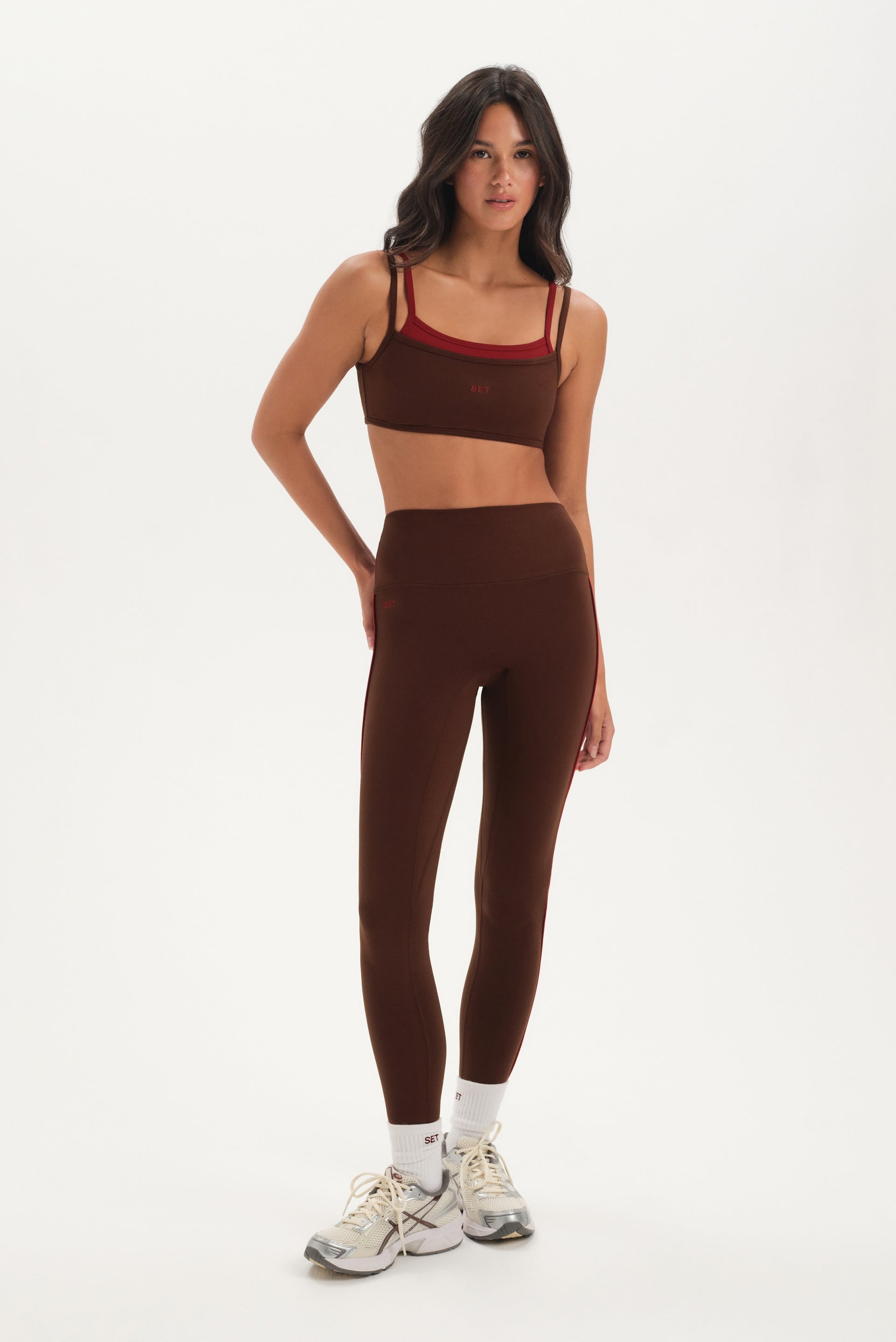 Woman wearing a brown sports bra and leggings set on a white background