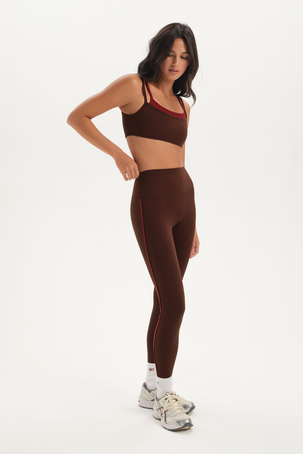 Woman wearing a brown sports bra and leggings set on a white background