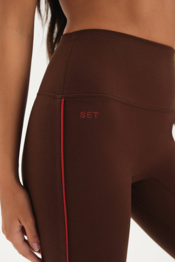 Brown leggings with a red stripe and 'SET' logo on a white background