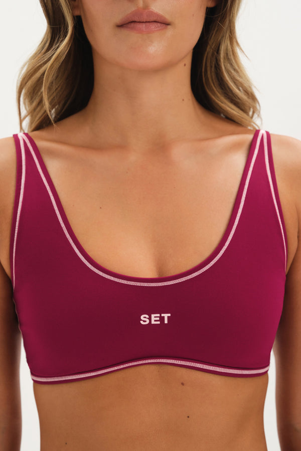 Maroon sports bra with white trim and 'SET' logo on a neutral background
