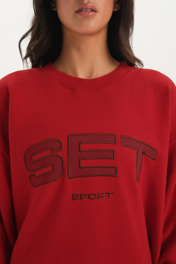 Red sweatshirt with 'SET Sport' text worn by a person