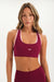 Woman wearing a maroon sports bra with pink straps on a white background <model-info>Bre wears a size S and is 5’7”, 25½" waist, 33” bust.</model-info>