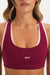 Maroon sports bra with pink straps worn by a person, featuring the brand 'SET'.